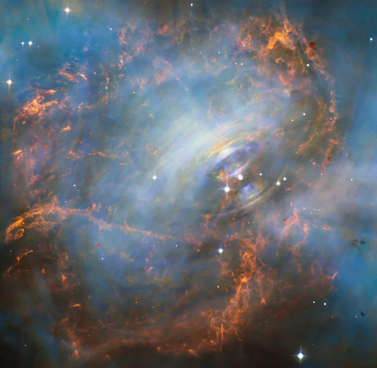 A close-up of the beating heart of the Crab Nebula, the pulsar and the ghostly blue wisps of energised gas whipping outward from it.