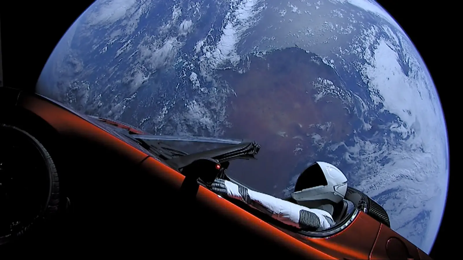 The Tesla Roadster with the Starman mannequin floating in space, with Earth in the background.