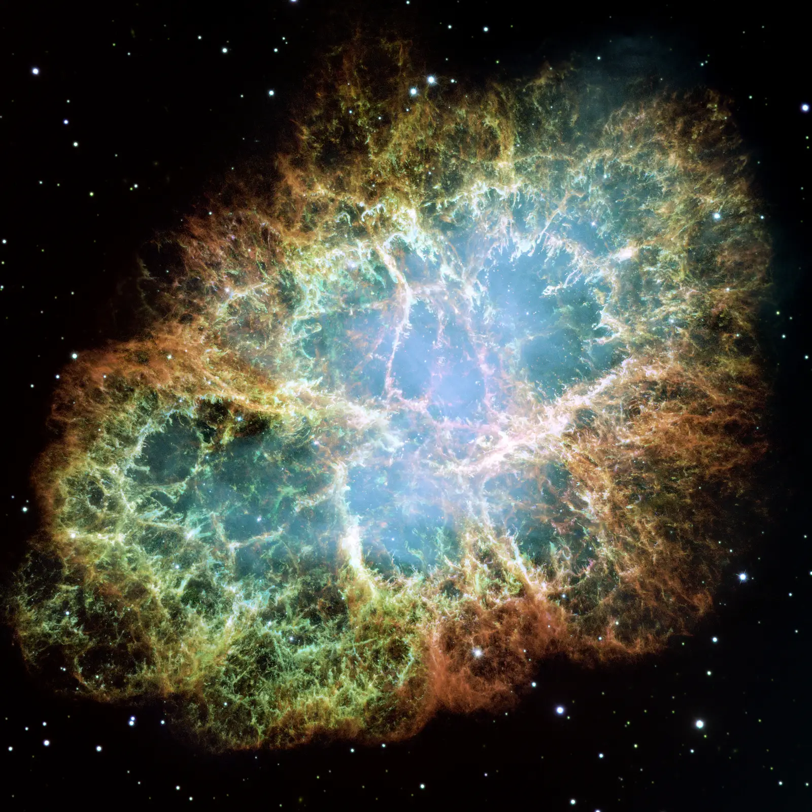 The Crab Nebula: a tangled oval cage of orange and green filaments around a blue-white glowing interior, the wreckage of the star that exploded in 1054.