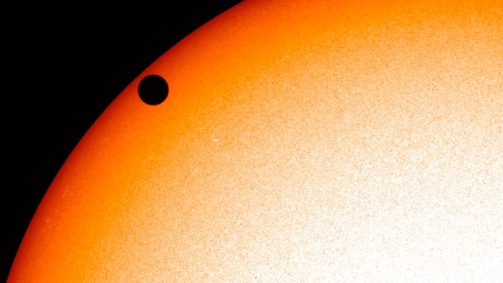 A close-up of the Sun’s disc during the 2012 transit of Venus, with the planet a small perfectly black circle silhouetted against the churning solar surface.