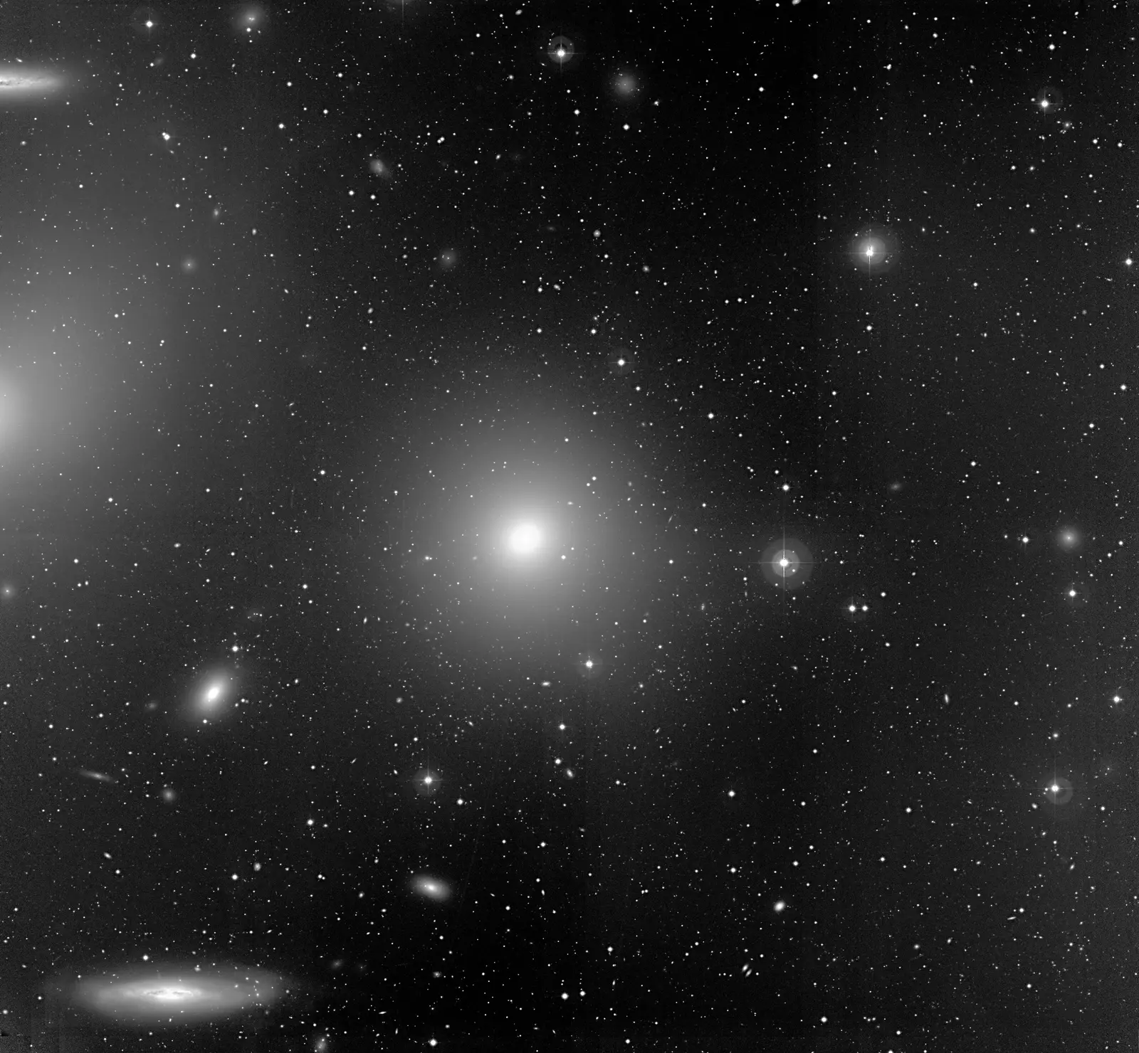 A crowded field of the Virgo Cluster imaged with the Wide Field Imager at La Silla: the giant elliptical Messier 84 at centre surrounded by many smaller galaxies, with the edge-on spiral NGC 4388 at lower left.