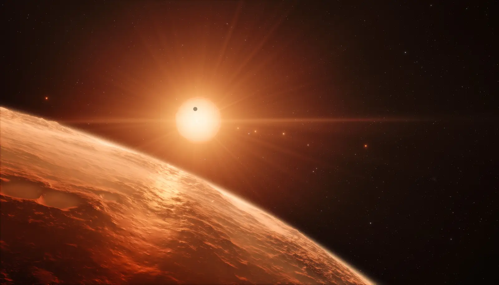 An artist’s view of the TRAPPIST-1 system: a dim red dwarf with several rocky, Earth-sized worlds strung close around it.