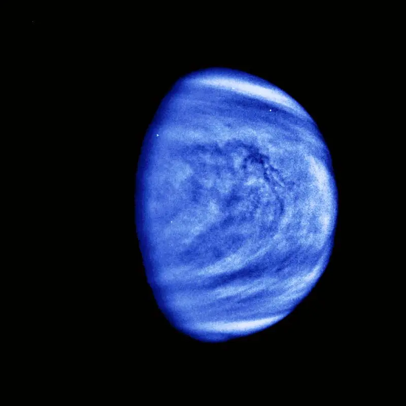 Venus as a single pale globe, its featureless sulphuric-acid cloud deck showing faint swirling bands, imaged in ultraviolet by the Galileo spacecraft.